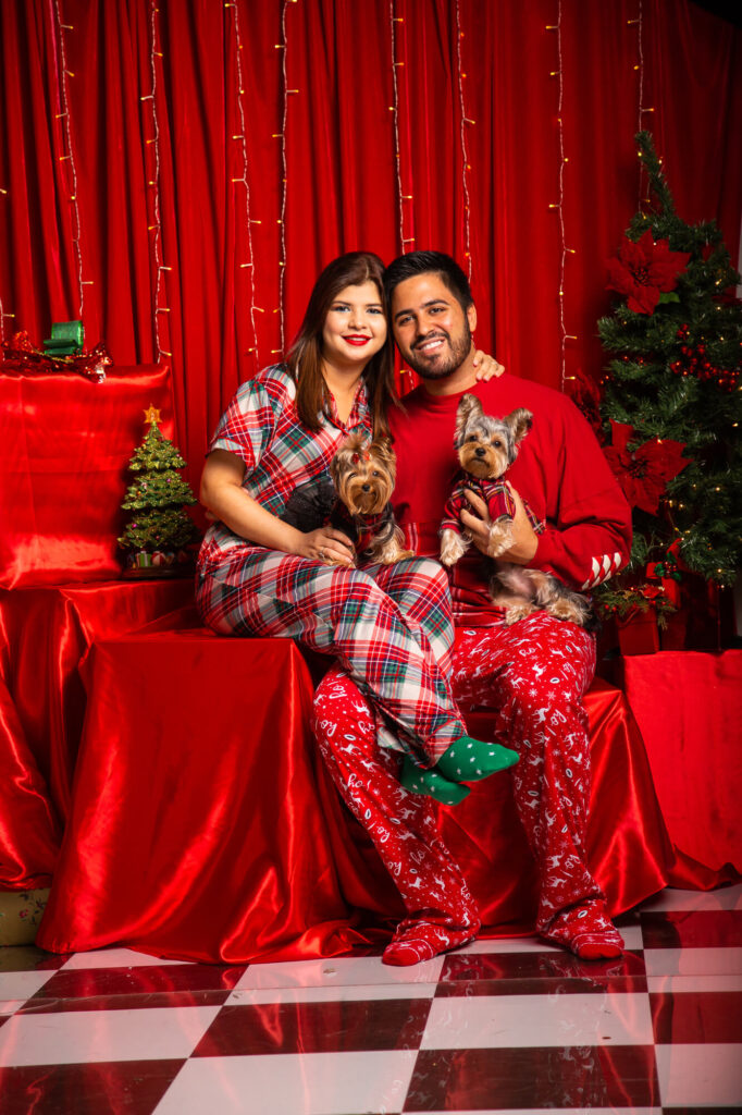 Sesión de Fotos en fondo rojo en estudio de Navidad Panamá 2022. Foto de pareja con dos Yorkies Mini